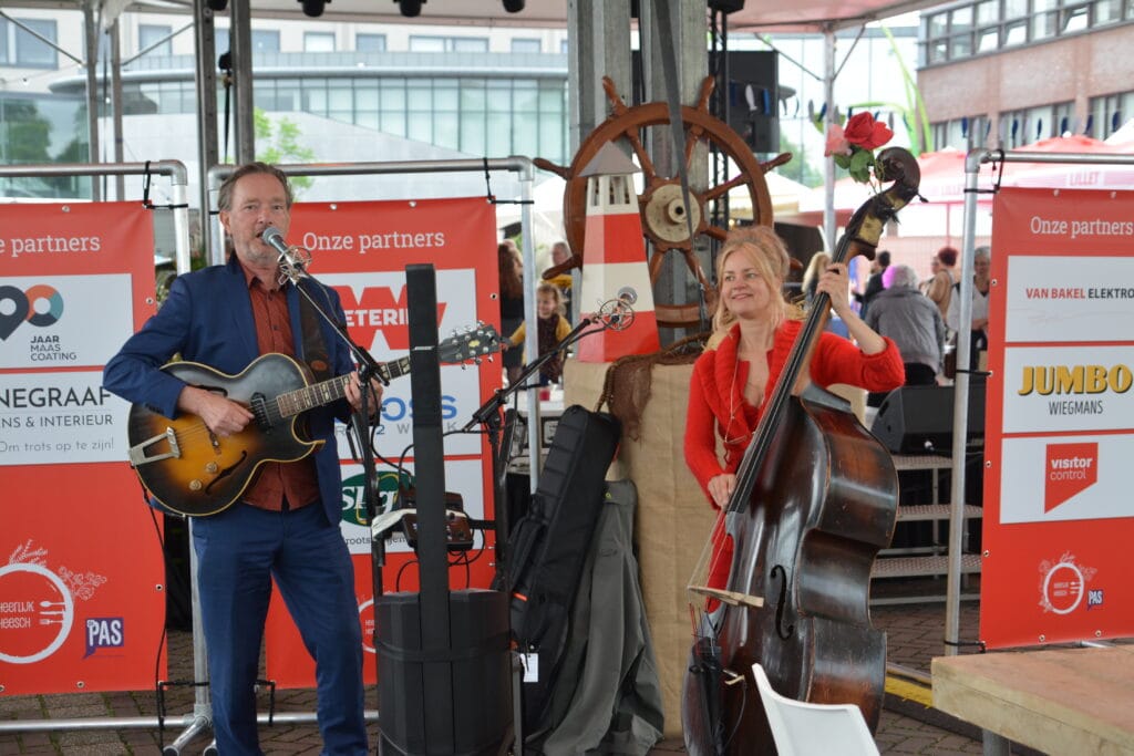 Muzikanten spelen live muziek tijdens Heerlijk Heesch, met een gitarist en een cellospeler in een ge.