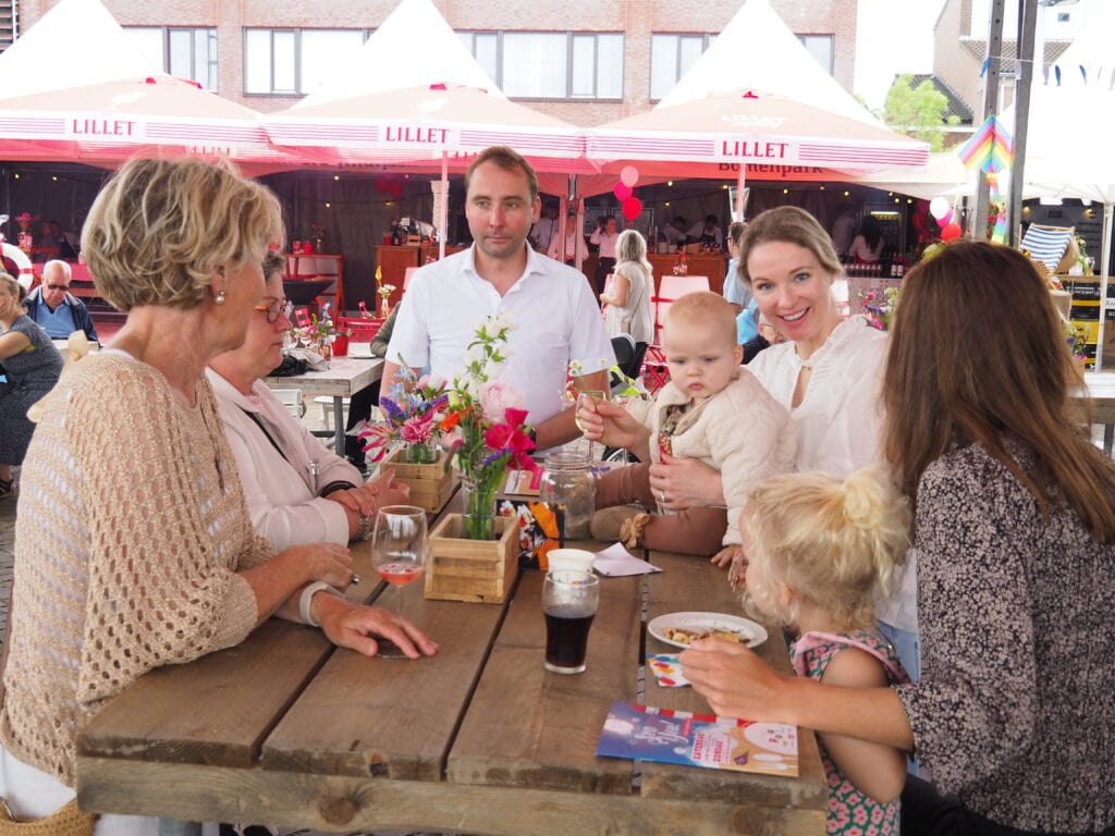 Gezellige familie met kinderen geniet van eten en drinken op terras in Heesch, met kleurrijke paraso.