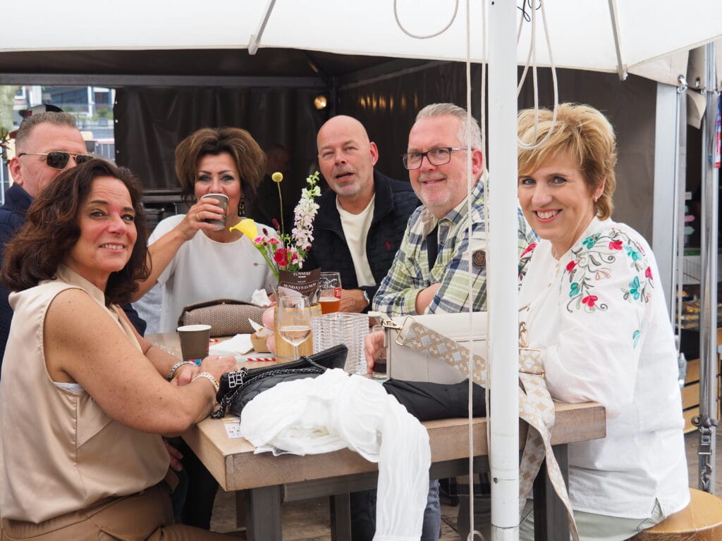 Groep mensen genietend van een drankje tijdens een buitenbijeenkomst in Heesch.