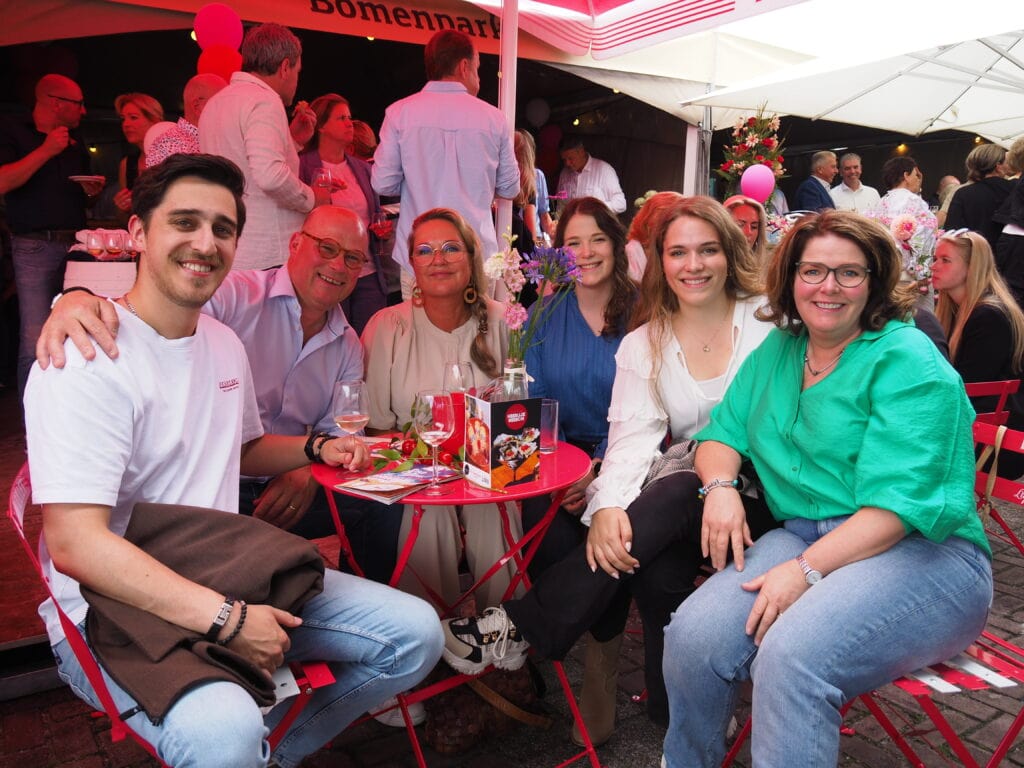 Gezellige groep mensen genietend van een drankje en gesprek op het terras tijdens Heerlijk Heesch.