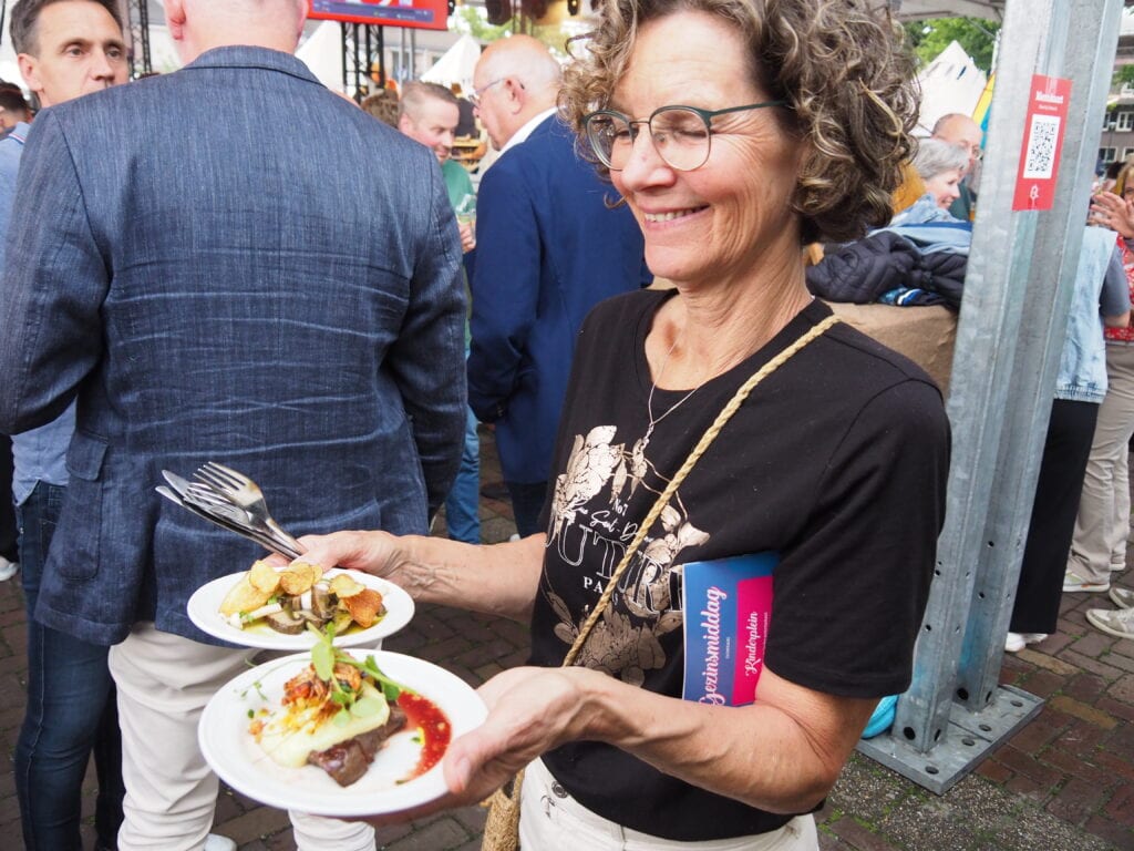 Vrolijke vrouw met smakelijk gerecht tijdens Heerlijk Heesch festival.