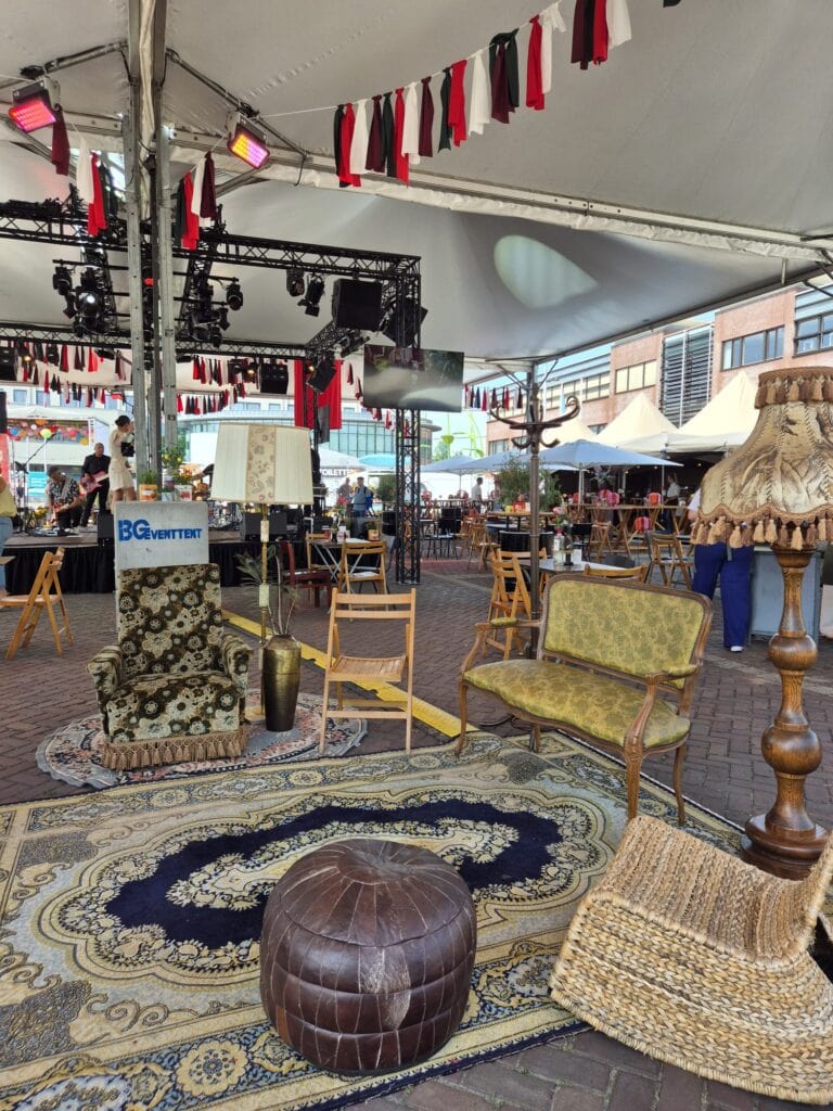 Vintage meubels en decoraties op de markt in Heerlijk Heesch, gezellige sfeer onder een grote tent.
