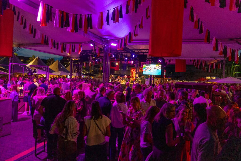 Sfeervol festival met veel bezoekers onder kleurrijke vlaggen in Heerlijk Heesch.