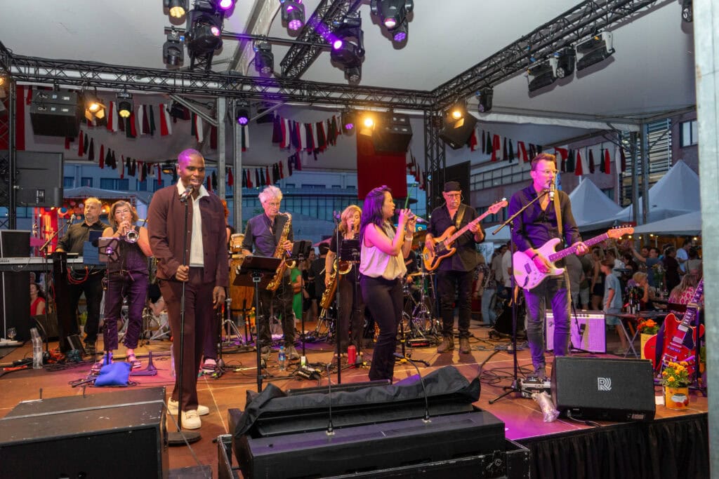Gezellige live muziekoptreden tijdens Heerlijk Heesch met band en zangers op het podium.