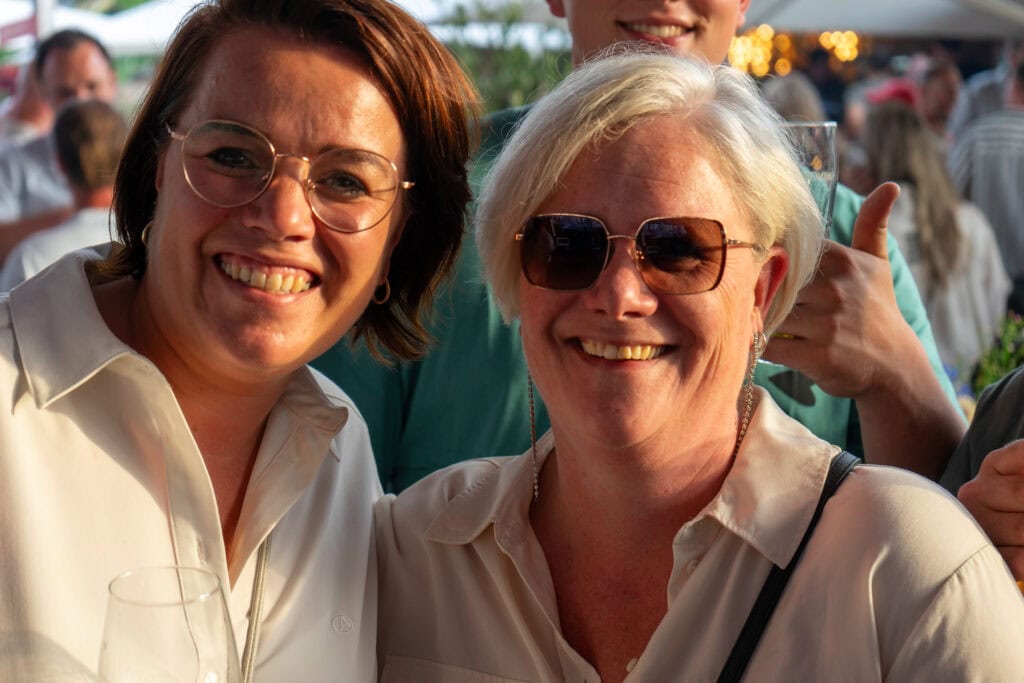 Gezellige mensen genieten van het feest in Heerlijk Heesch, met lachende gezichten en zomerse sfeer.
